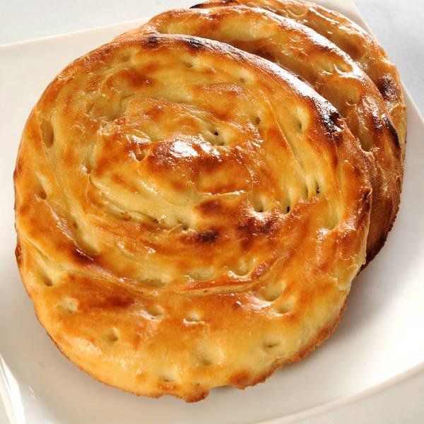 a round, golden-brown baked item. It appears to be freshly baked and is placed on a white plate or surface is called Sheermal